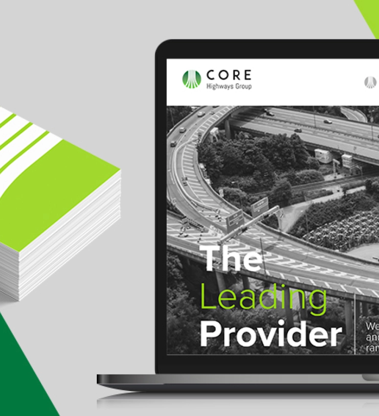A laptop screen showing the new website design for Core Highways Group and a pile of business cards showing the new branding and logo Fabrick's creative team designed