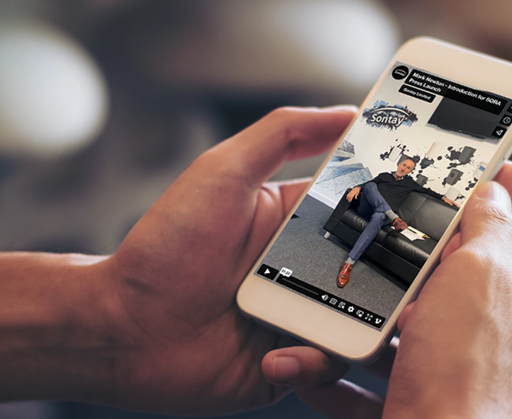 person holding a mobile phone that displays Sontay's SORA launch video